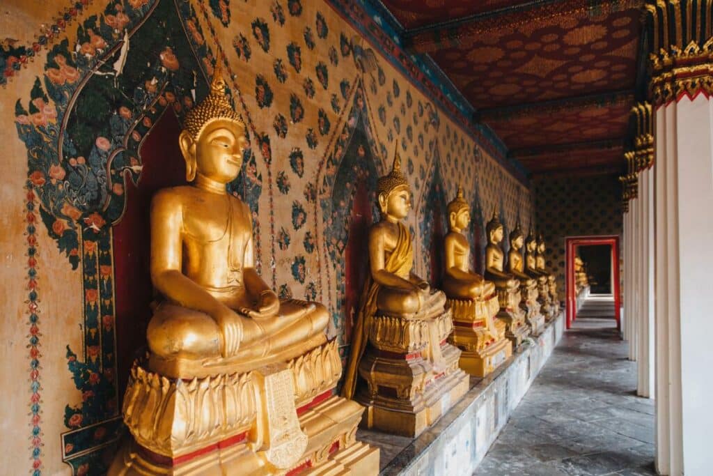 Row Of Golden Buddha Statues In A Bangkok Temple Gallery Corridor