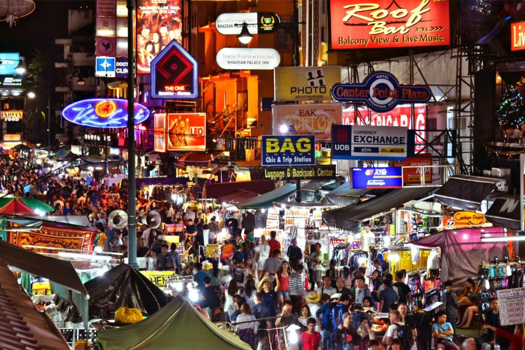 Khaosan Road Bangkok At Night With Neon Signs, Market Stalls, And Crowds