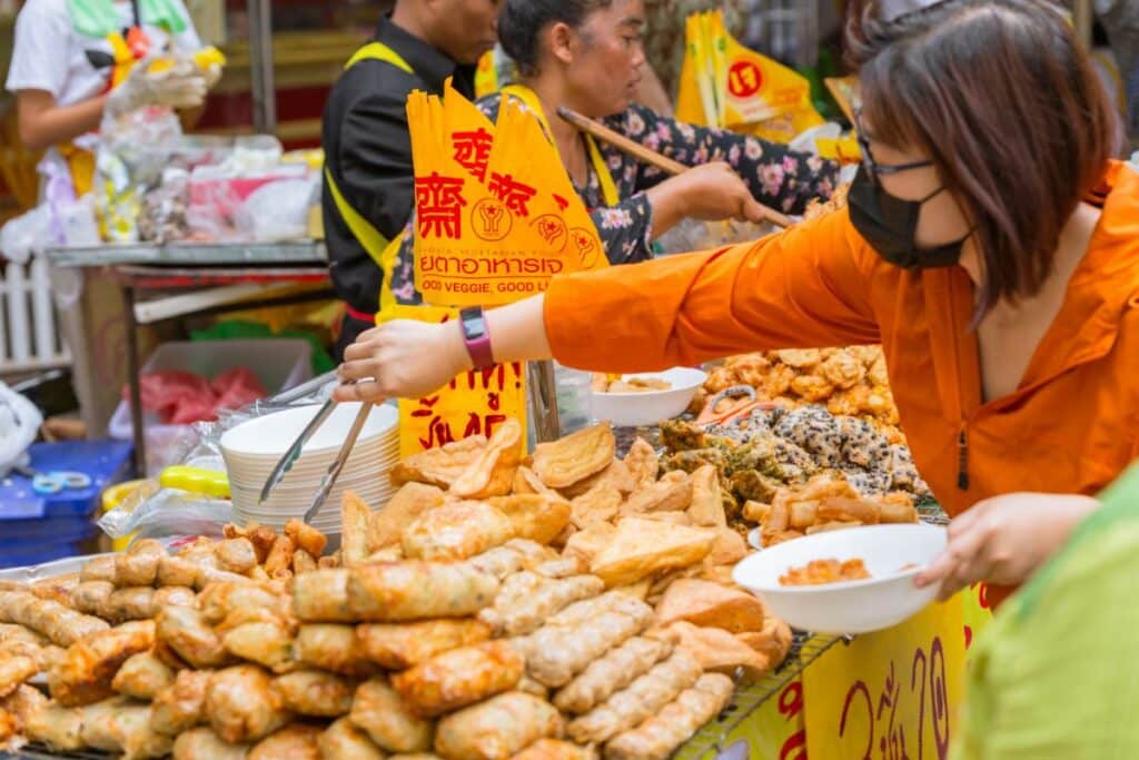 Bangkok Street Food Vendor Stall With Fried Snacks And Vegetarian Festival Flags